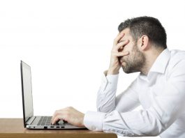 Frustrated man in front of a laptop.